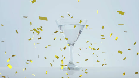 Golden-confetti-falling-over-olives-falling-into-cocktail-glass-against-grey-background