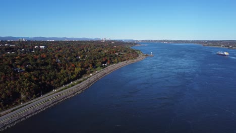 ciesz się z zapierających dech w piersiach widoków z powietrza, gdy dron unosi się nad rzeką saint-laurent w quebecu, uchwycając oszałamiającą jesienną scenerię, drogę przecinającą rzekę i las poniżej