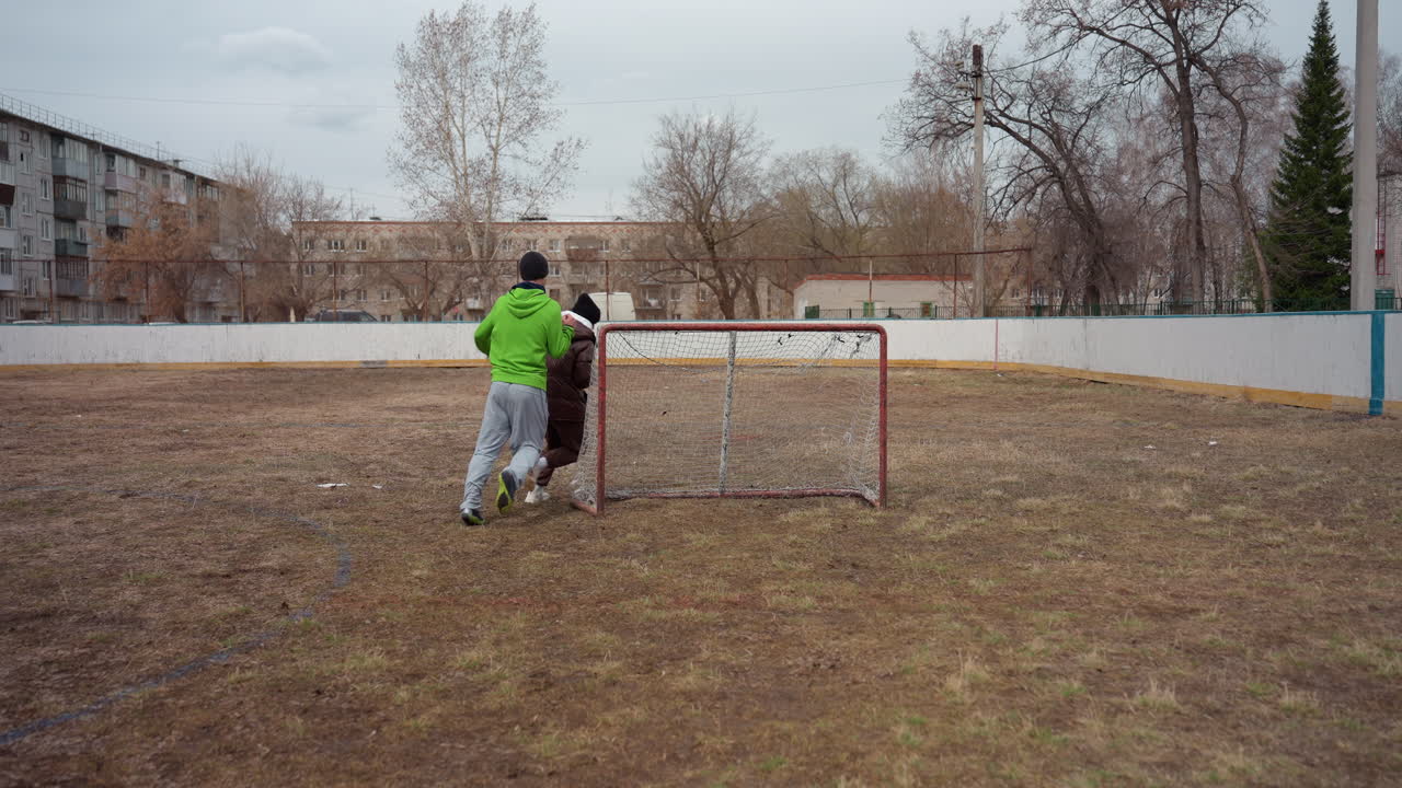 entusiasmo por el fútbol juvenil, adolescentes esprintando hacia una oportunidad de marcar, jóvenes atletas persiguiendo el balón en un terreno embarrado, niños compitiendo apasionadamente durante un enérgico partido de fútbol al aire libre