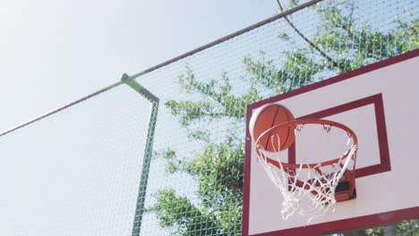 Flying-ball-on-sunny-basketball-court,-in-slow-motion