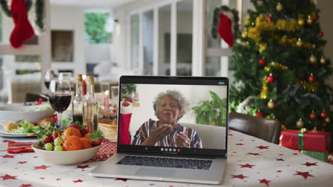 feliz afroamericana mujer mayor en la computadora portátil acostada en la mesa de navidad