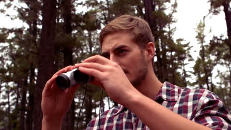 man hiking through a forest using binoculars