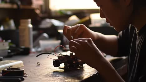a young inventor focuses intently on assembling a robot prototype in a busy workshop. tools and materials are scattered around as they connect wires and components, creating something innovative.