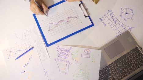 male hand draws business graphs on a white paper.