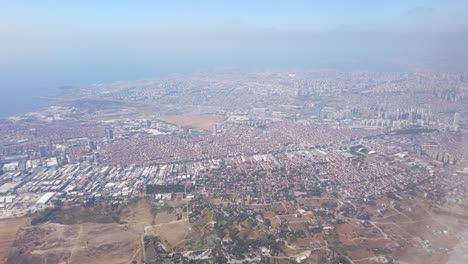 in the daytime, a view of istanbul city through the airplane window, showcasing a dense cityscape and the coastal shoreline