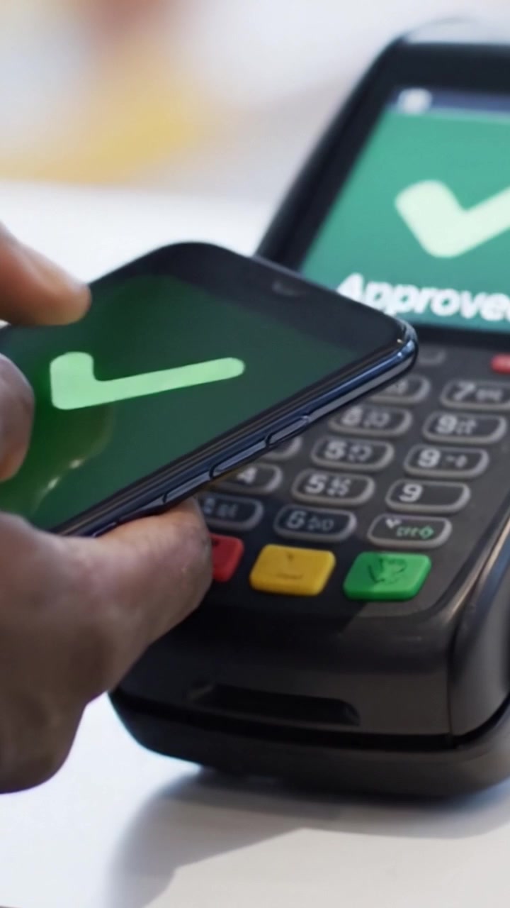 Contactless Payment: A User Approves Transaction Using Smartphone Near Card Reader, Demonstrating Modern Digital Payment Technologies and Seamless Transactions.