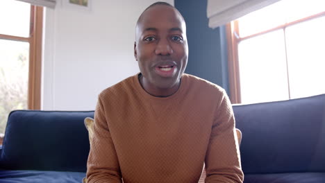 Happy-african-american-man-sitting-on-sofa-having-video-call-at-home,-slow-motion