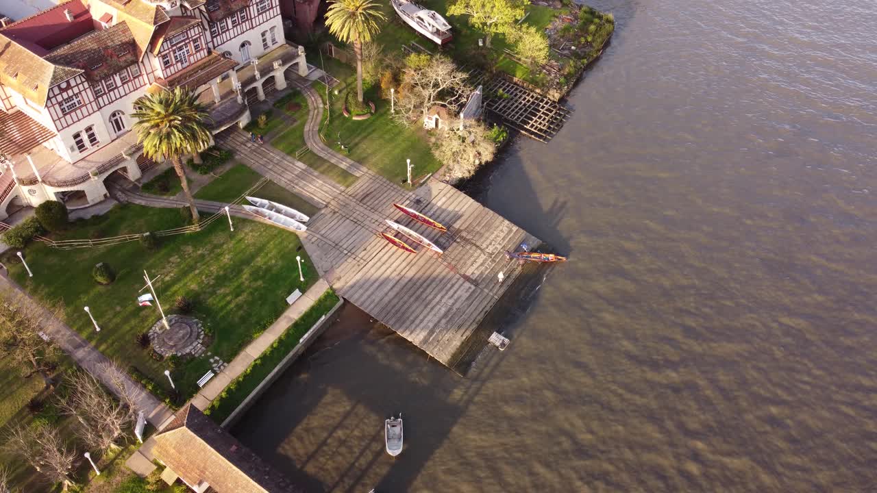 부에노스아이레스 일몰 때 티그레 강의 노젓는 배를 정박하는 사람들의 공중 하향식 샷 - 강변의 목조 부두에 도착