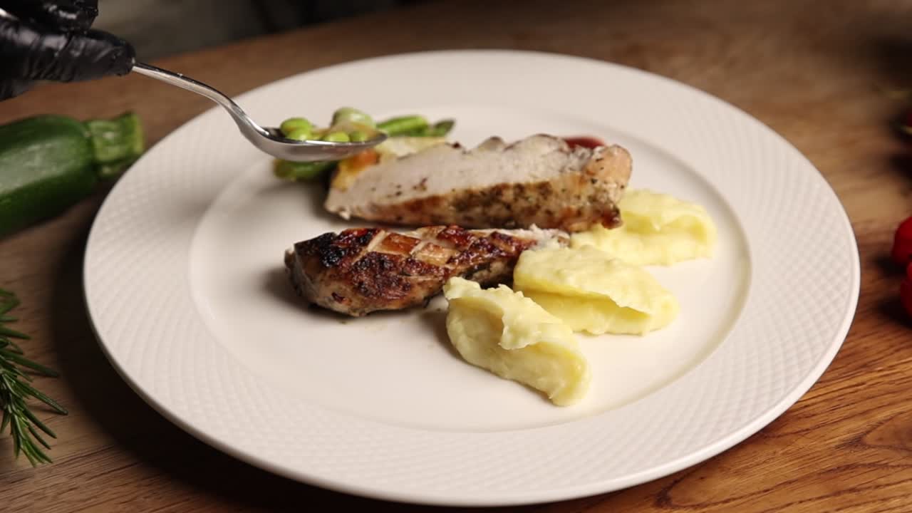 Chef che serve un piatto gourmet di pollo con purè di patate e verdure