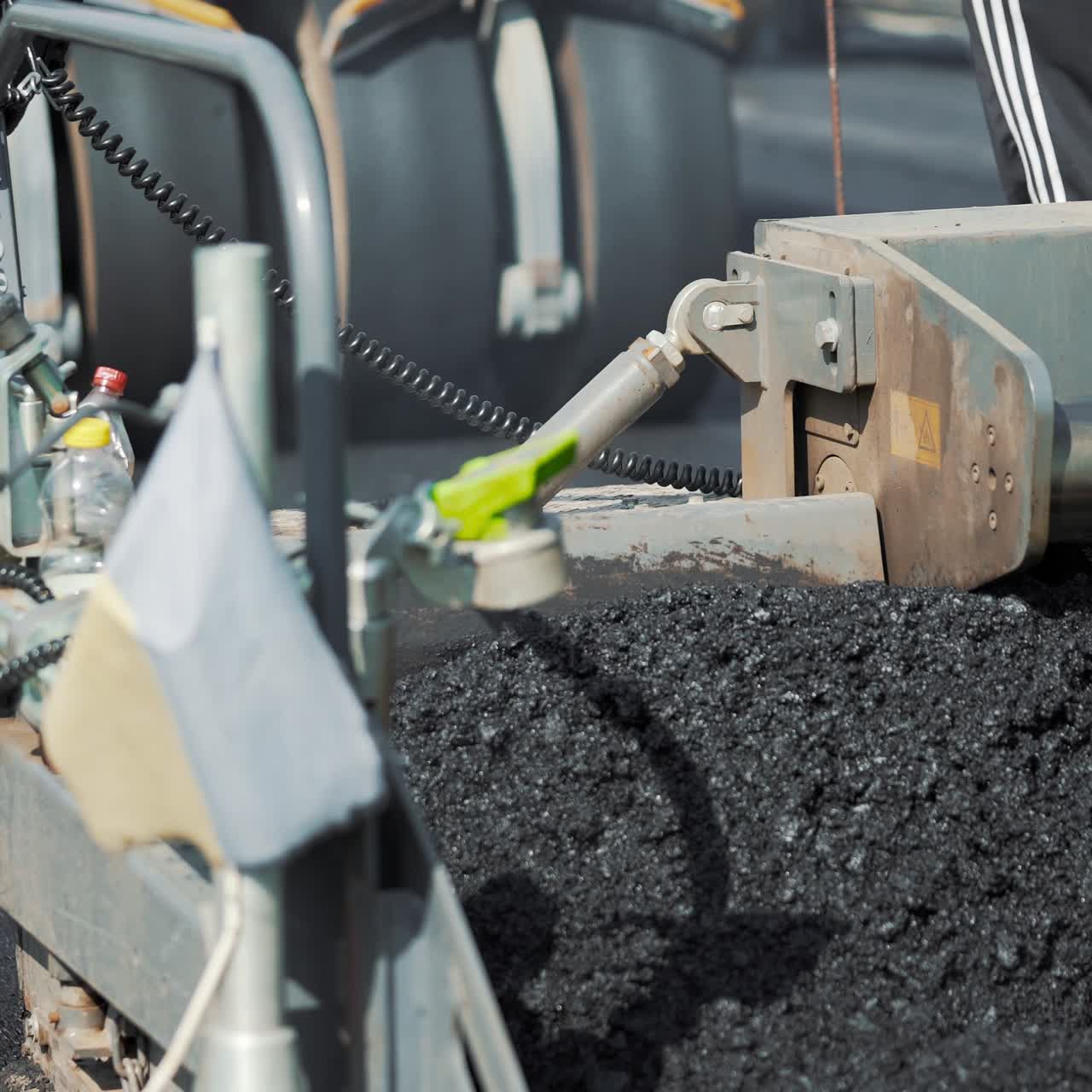 professional equipment is mixing bitumen and putting the mixture on the road on the background of a passing roller machine