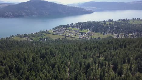 La-Vista-Aérea-Sobre-Una-Cresta-Boscosa-Muestra-Una-Pequeña-Comunidad-Junto-Al-Lago.