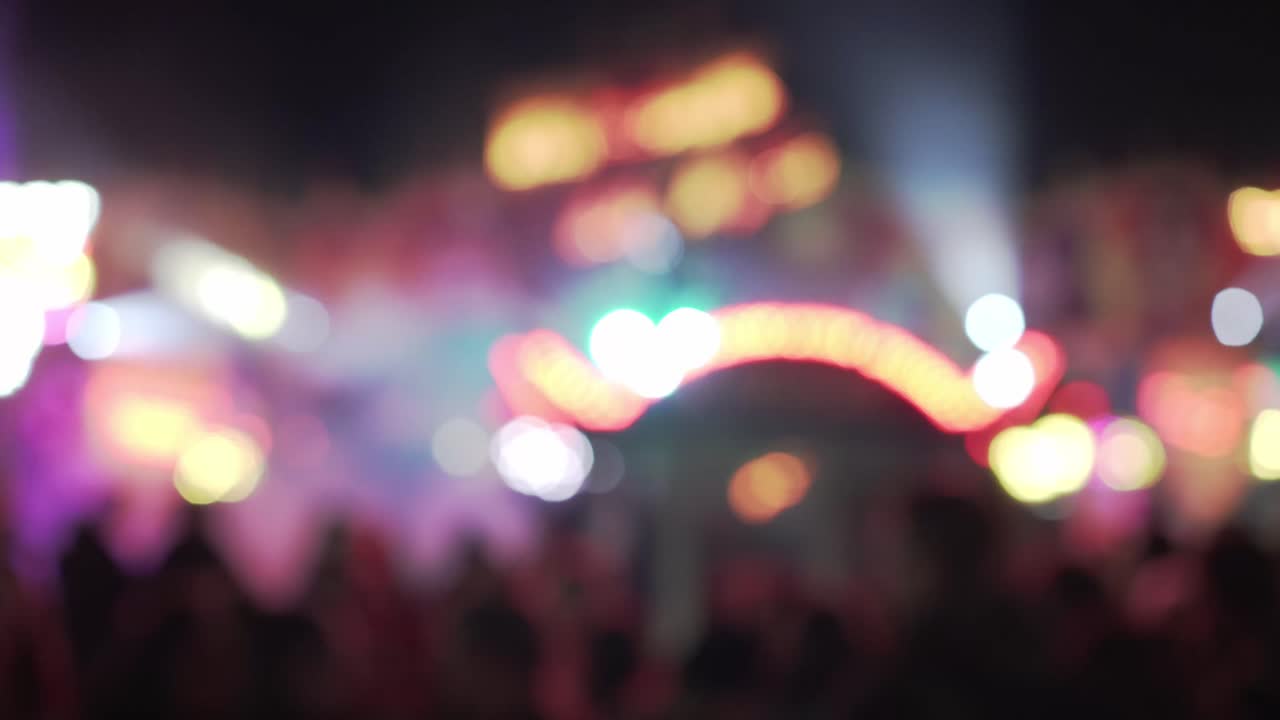Blurry lights of carnival fair party at night and people