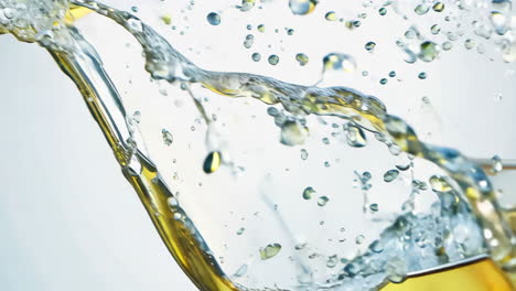 clear liquid splashes in mid-air on a light background. water droplets and liquid gracefully leap in the air, creating an artistic display of motion against a soft backdrop.