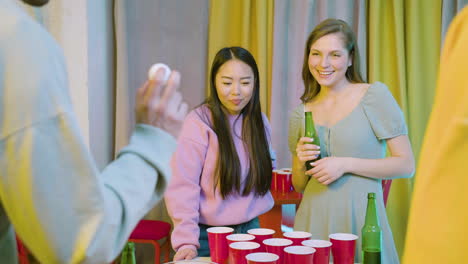 felici giovani amici multietnici che giocano a beer pong a casa