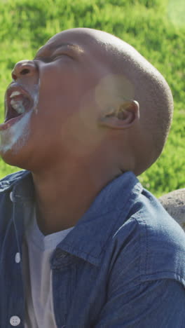 video of happy african american boy eating ice creams and laughing on sunny day