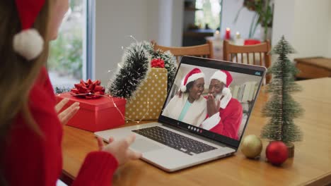 Happy-caucasian-woman-on-video-call-with-senior-couple-at-christmas-time