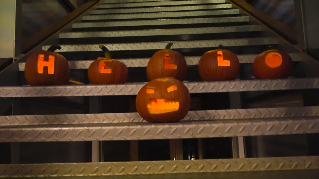 할로윈 호박은 조각이 있고 좋은 그림자와 함께 밤 동안 회색으로 된 금속 계단에 인사라는 단어를 표기합니다.