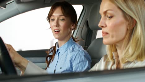 women discussing a car in a showroom