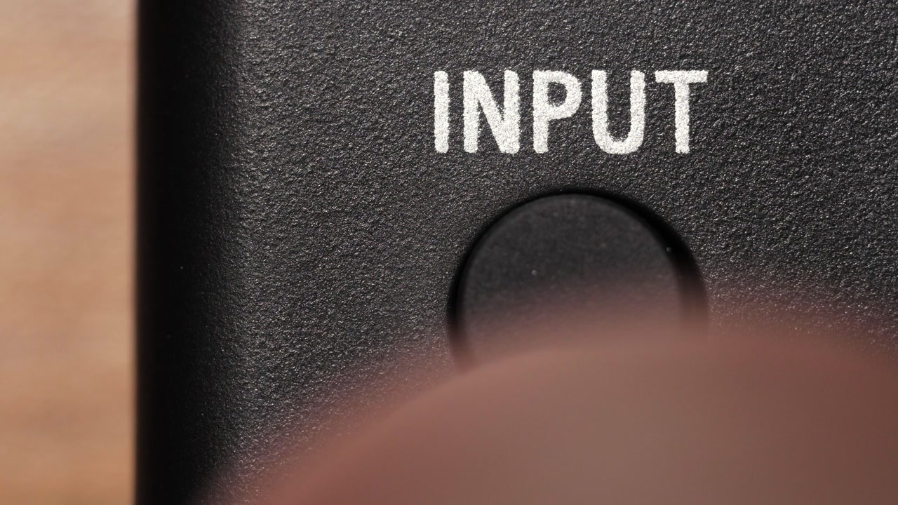 Macro view of finger pressing black input button below white text on black panel