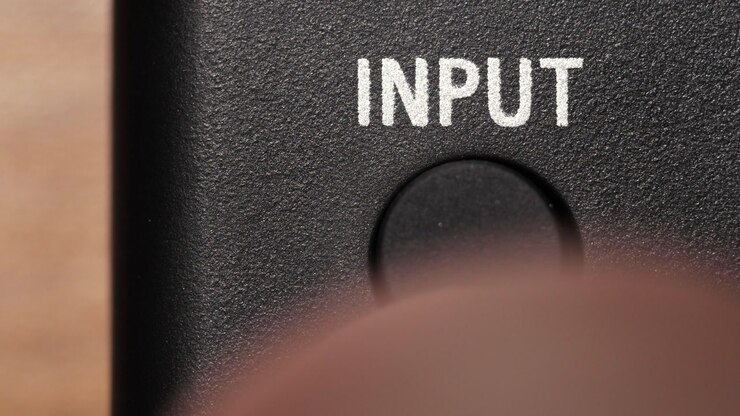 Macro view of finger pressing black input button below white text on black panel