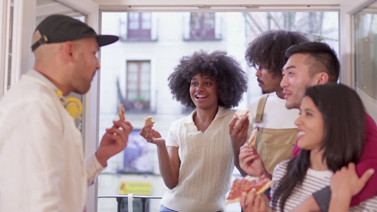 Diverse group of friends enjoying pizza and socializing on a balcony