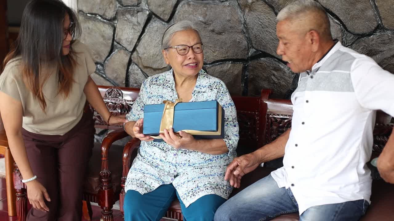 padre y hija asiáticos ancianos sorprenden a la madre con una caja de regalos y flores en una ocasión especial