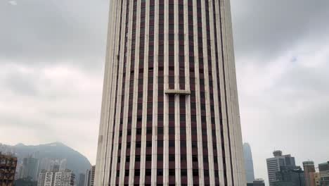 timelapse, suspended platform rising on hopewell centre skyscraper in hong kong on a gloomy day