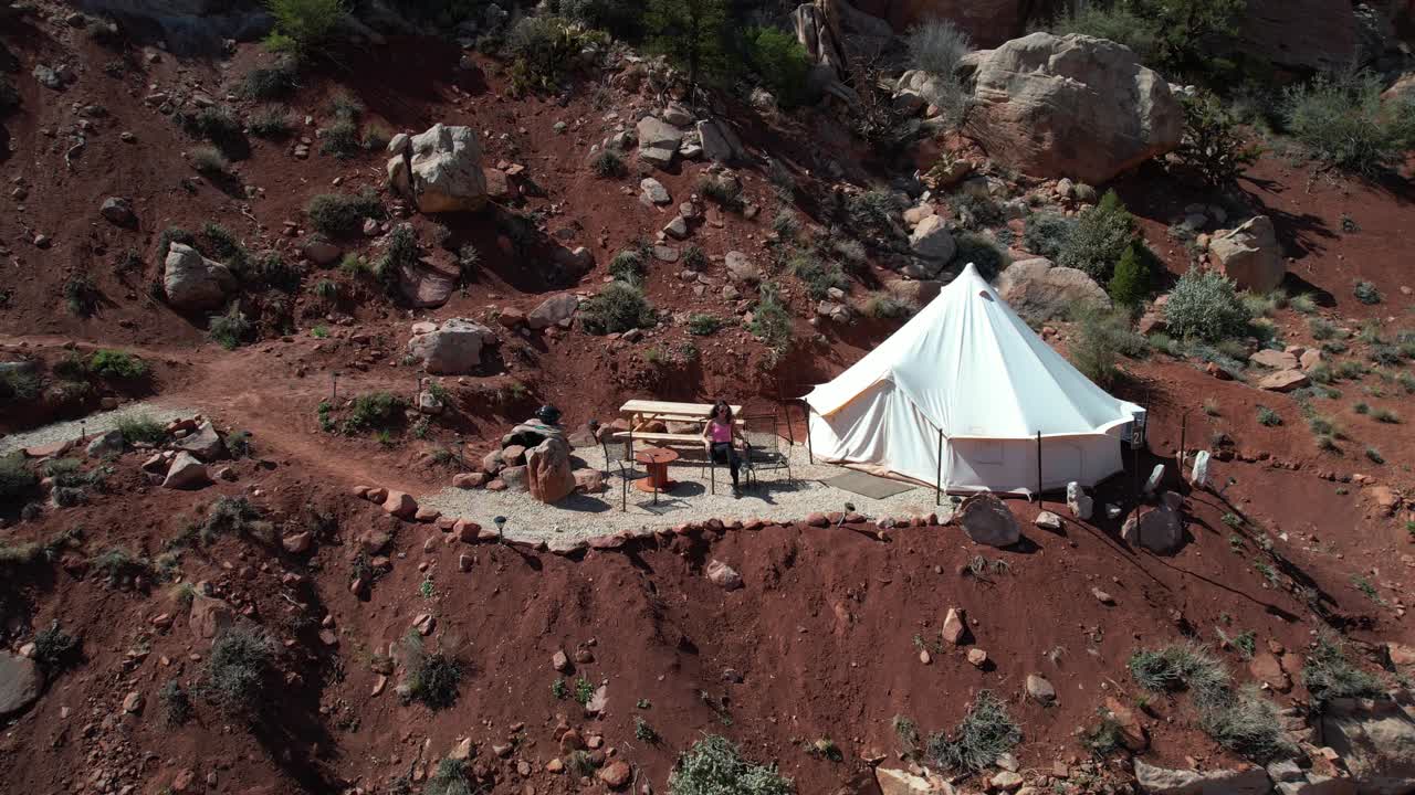 tomada de dron de una mujer joven saliendo de la tienda de la yurt en el área de glamping y el paisaje del parque nacional de zion, utah, ee.uu.