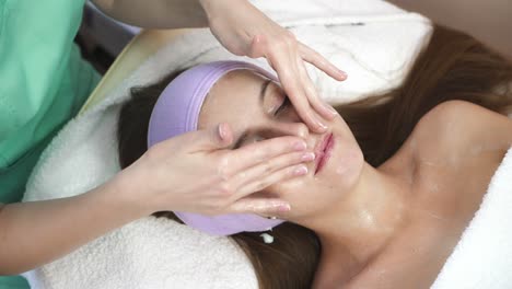 woman during facial massage. young woman relaxing during rejuvenating facial massage in beauty center