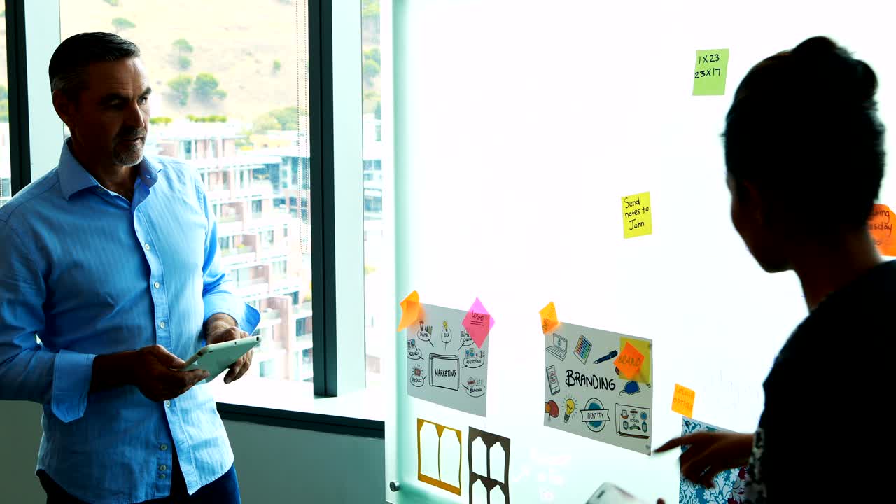 executivos a ler notas adesivas em placas de vidro.