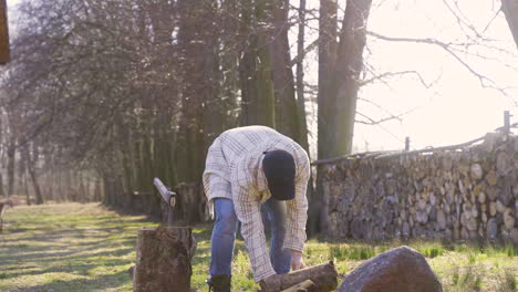 caucasian chopping firewood with an ax outside a country house