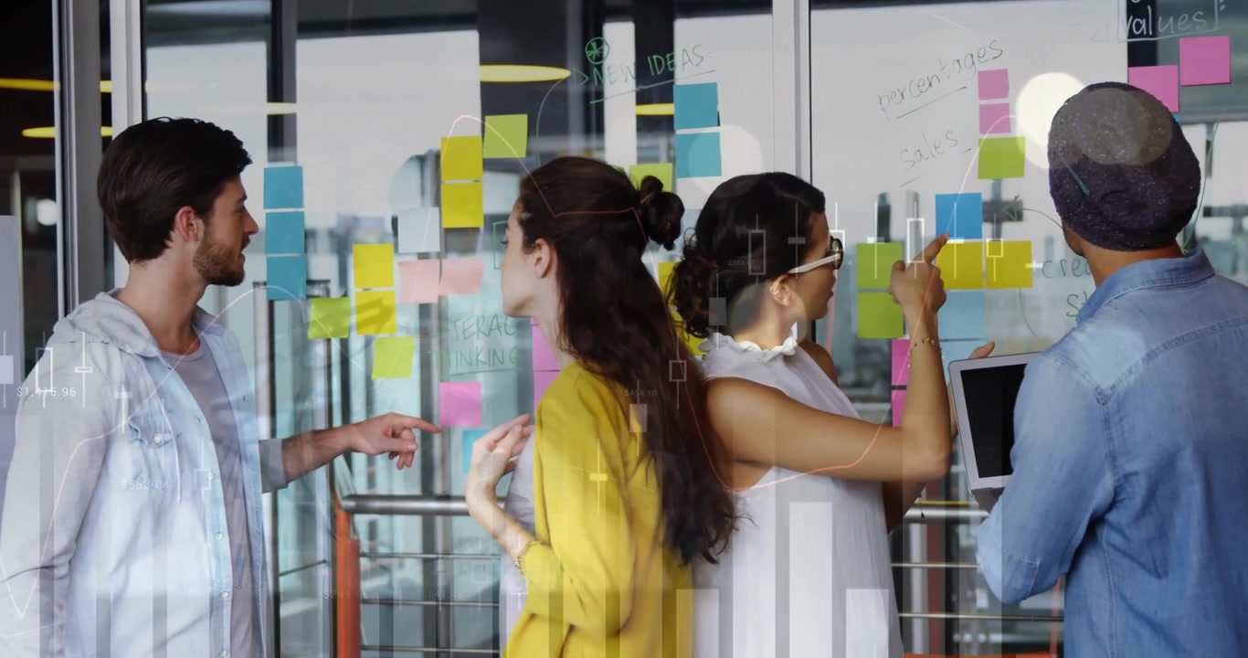 four colleagues brainstorming on marketing glass wall of sticky notes, showing floating sales chart