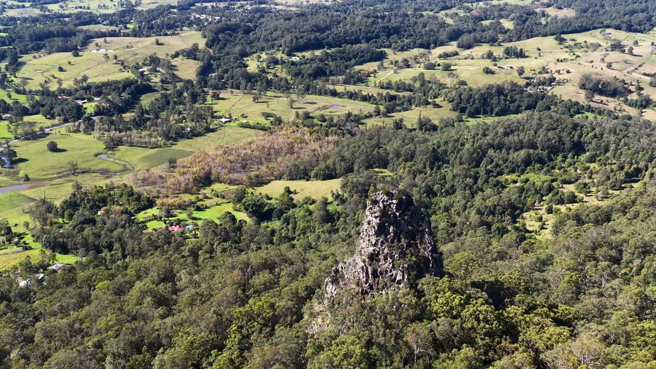 Aerial footage captures the iconic Nimbin Rocks amidst lush greenery and rolling hills under bright daylight in Nimbin, NSW