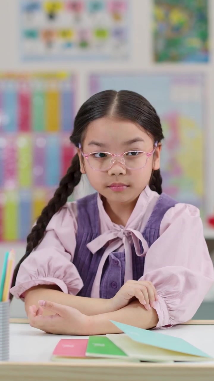 Scolara asiatica stanca si sveglia da un pisolino al banco della classe, con un'espressione annoiata sotto un'illuminazione chiara e uniforme.