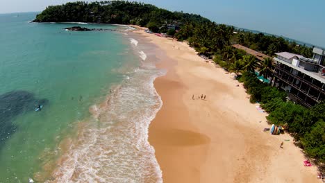 imágenes aéreas de una amplia playa de arena con grandes olas oceánicas que llegan y rompen en la bahía de la hermosa isla de sri, sri lanka