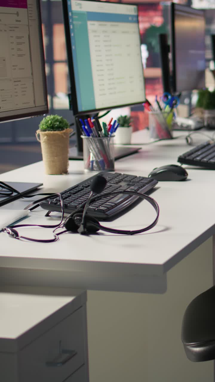 Vertical video Audio headsets and compute peripherals on office desk, close up