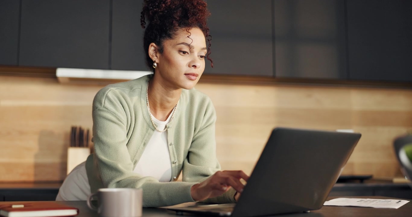 Young Woman Working on Laptop in Modern Kitchen