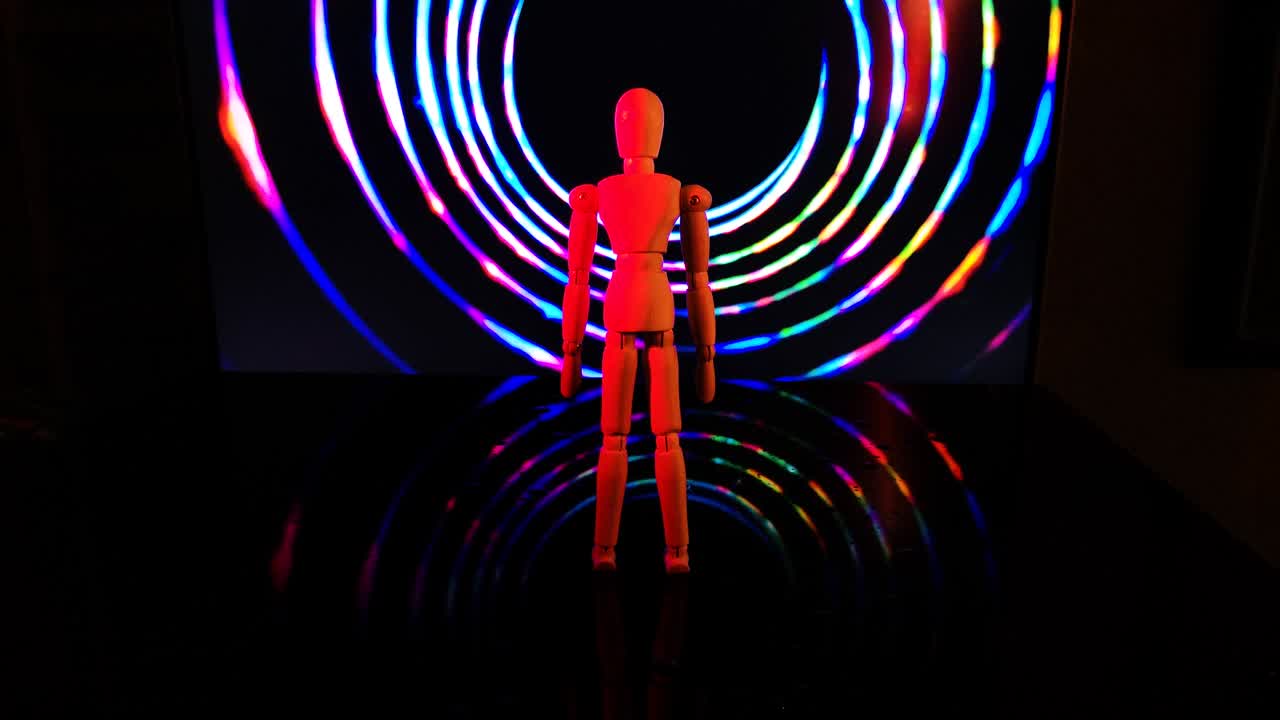An articulated man stands in front of a rotating multicolored funnel
