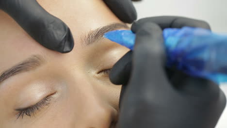 permanent tattooing of eyebrows. cosmetologist applying permanent make up on eyebrows