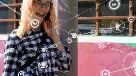 animation of network of connected icons in circles over happy caucasian woman using smartphone