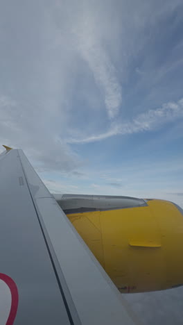 view from a plane window of the sky with the wing of the plane in shot in vertical