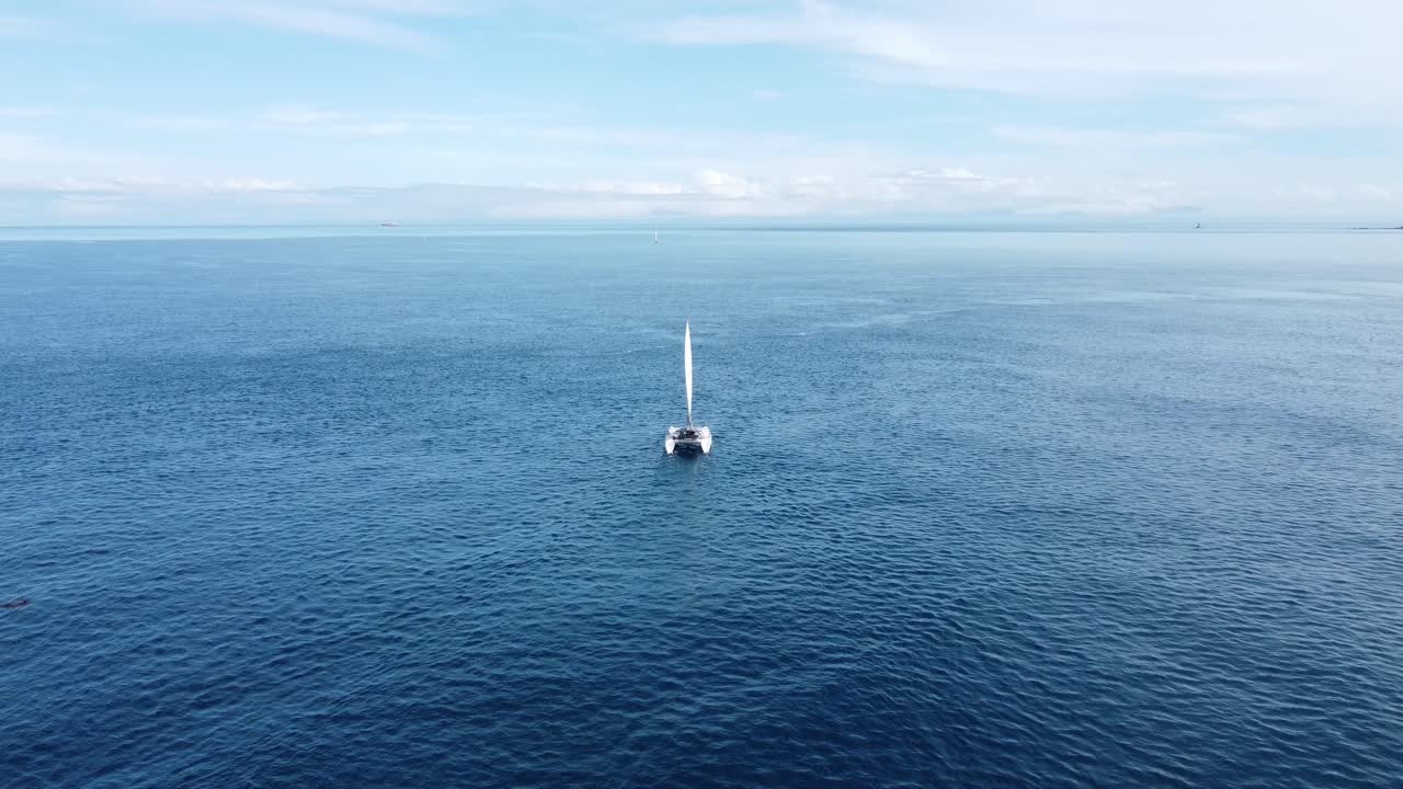 잔잔하고 평평한 바다를 항해하는 작은 요트를 향해 날아가는 것