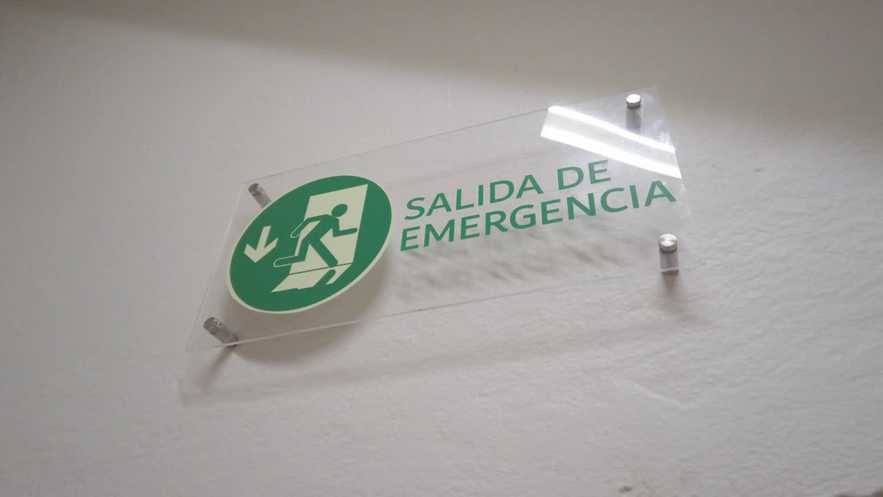 Handheld shot of emergency exit sign written in spanish, indoor, medium shot