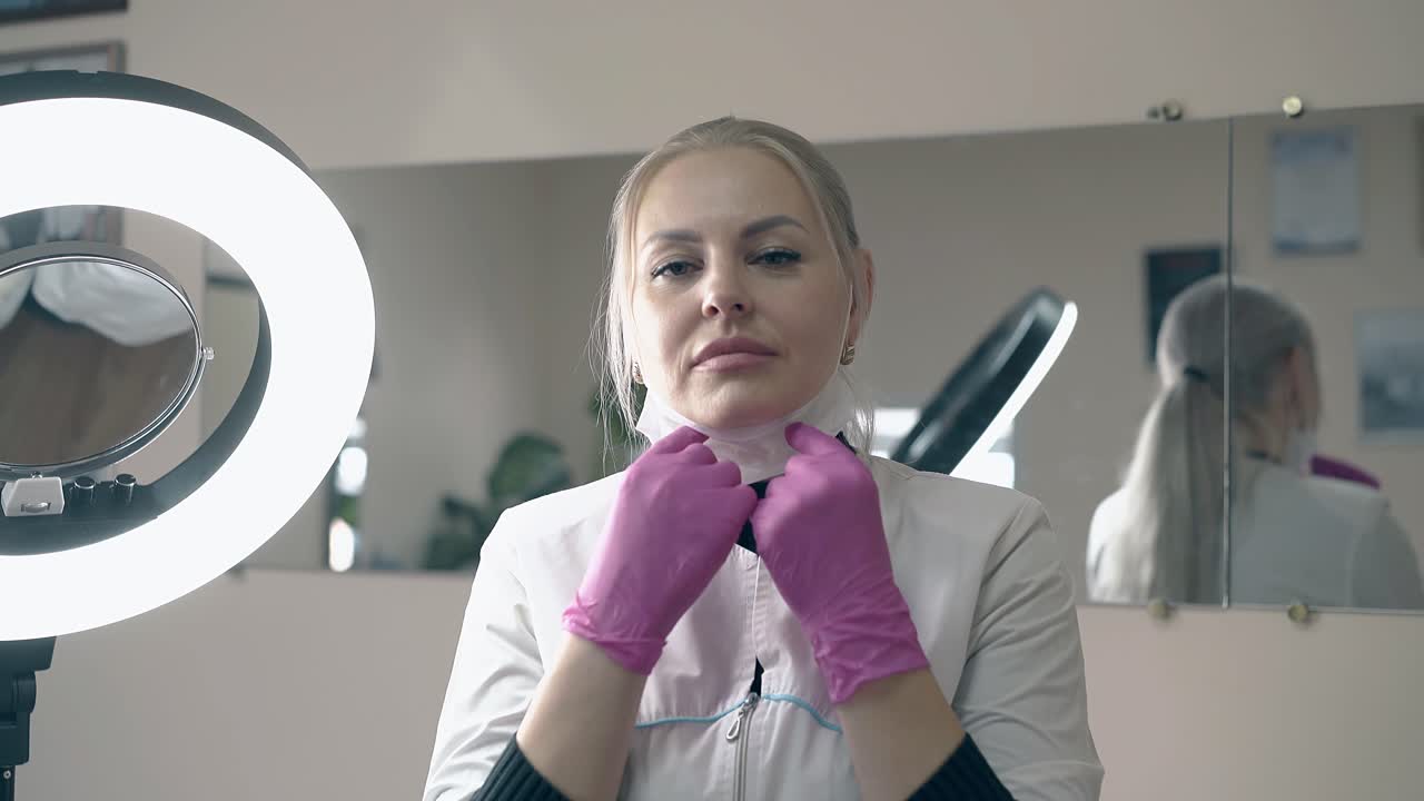 Kvinde i hvid kittel og handsker tager maske af i salon