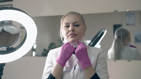 woman in white coat and gloves takes off mask in salon