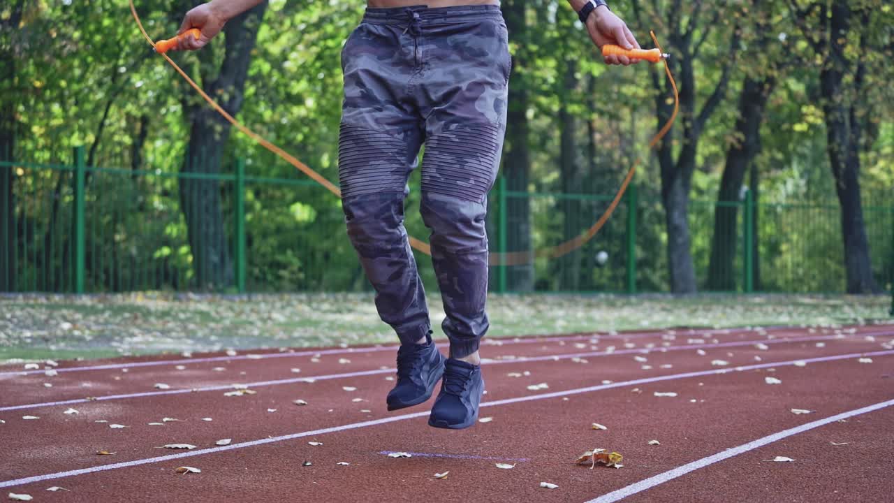 Close up of man with jumping rope. Sportsman jumping on skipping rope during workout at city stadium