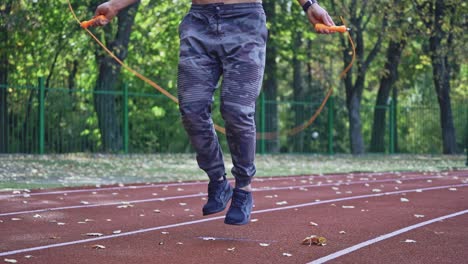 close up of man with jumping rope. sportsman jumping on skipping rope during workout at city stadium