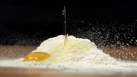 egg pouring onto flour on table