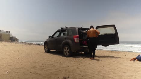 un surfista poniéndose un traje de neopreno mientras se prepara para salir al océano