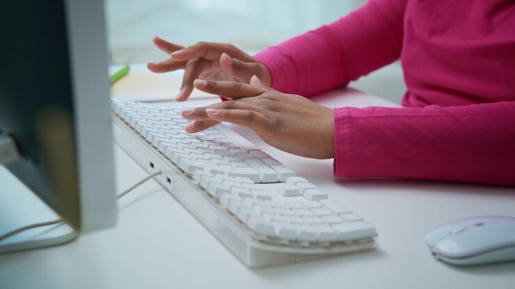 Person Typing on White Computer Keyboard at Desk